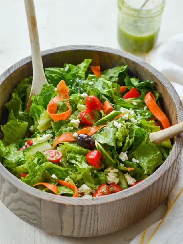 A plate of lettuce salad with carrots and tomatoes